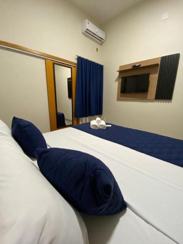 a bedroom with a bed with blue pillows on it at Visionsul Hotel in Chapadão do Sul