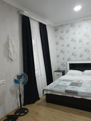 a bedroom with a bed and a fan next to a window at Akhaltsikhe hotel “Sunny House” in Akhaltsikhe