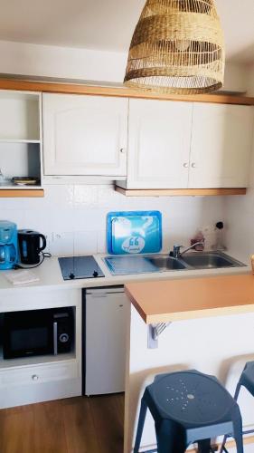 une petite cuisine avec des armoires blanches et un évier dans l'établissement Les Grands Yatchs avec Parking, à La Rochelle