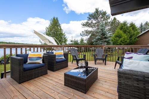 a deck with couches and chairs and a table at Lake House Chalet Laurentians in Nominingue