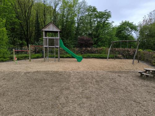 a playground with a green slide and a bench at Hotel Grünwalde in Halle Westfalen