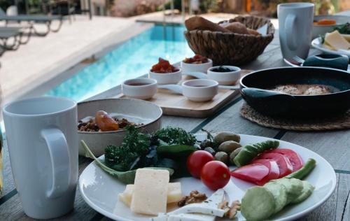 a table topped with plates of food next to a pool at Kikonia Art & Suites in Akyaka