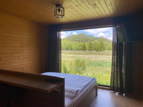 a bedroom with a large window with a view of a field at La AMI Kaban in Câmpulung Moldovenesc