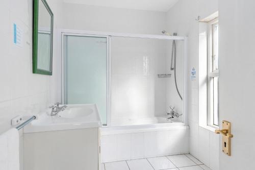 Un baño blanco con lavabo y ducha. en Summerville 20 by Host Agents, en Ciudad del Cabo