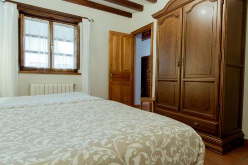 a bedroom with a bed and a large wooden cabinet at El Molino de Bonaco in San Vicente de la Barquera
