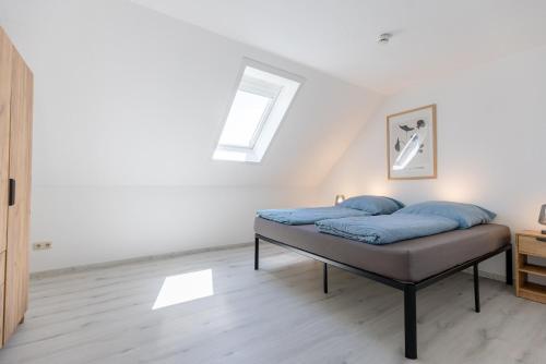 1 cama con almohadas azules en una habitación blanca en Pitlane-Apartment 2, en Herresbach
