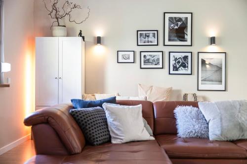 a living room with a brown leather couch with pillows at Villa von Maximus in Leipzig