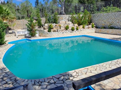 a swimming pool in a backyard with a stone wall at Kalokairia Residence in Gaios