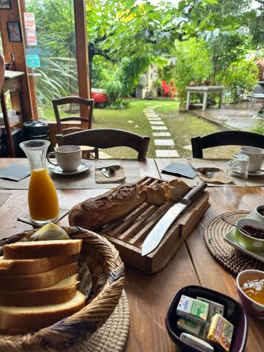 a wooden table with a basket of bread and orange juice at Le Mazet des Beaujots in Monteux