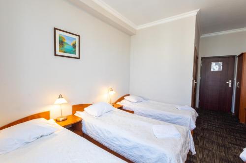 a hotel room with three beds with white sheets at Noclegi Stadion Bed & Breakfast in Warsaw