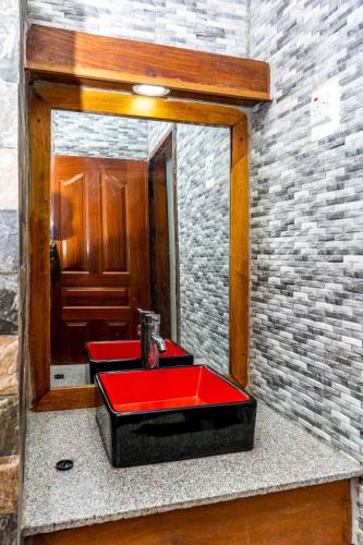 a bathroom with a red sink in front of a mirror at Oasis of Bliss Diani Beach Apartment in Ukunda