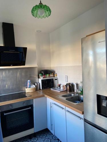 une cuisine avec un réfrigérateur en acier inoxydable et un évier dans l'établissement Chambre Double Élégante Proche de Paris, à Drancy