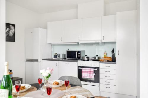 a kitchen with white cabinets and a table with glasses of wine at Central Big and Bright Resting place in Trondheim