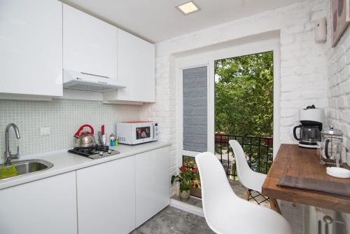 a white kitchen with white cabinets and a balcony at Art Studio 2 in Tashkent