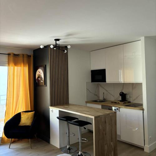 une cuisine avec des armoires blanches et un comptoir avec des tabourets dans l'établissement studio Natureva accès piscine 224 B - Luxe - 2 personnes, au Cap d'Agde