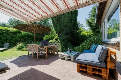 een patio met een parasol en een tafel en stoelen bij Poldersbos 7 - Ouddorp NOT INTENDED FOR COMPANY OR WORK-RELATED STAYS in Ouddorp