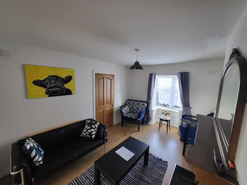 Una sala de estar con un sofá negro y una silla. en Fortlands, en Kiltimagh