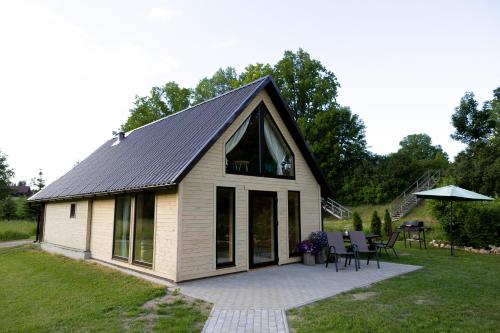 a house with a gambrel roof and a patio at Kalna Smīžu pirtiņa in Melturi
