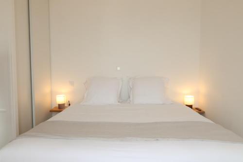 a bedroom with a white bed with two lamps at Le Clos Normand in Saint-Aubin-sur-Mer