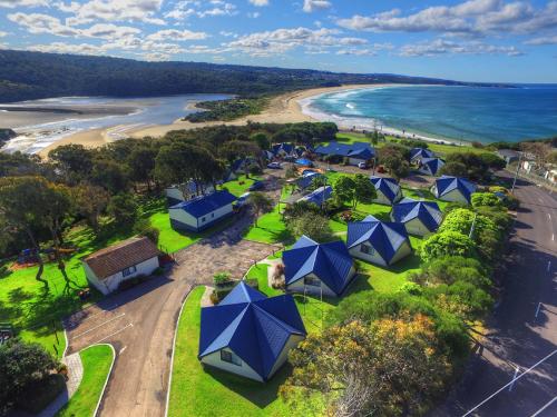 a beach filled with lots of green lawn chairs at Beach Cabins Merimbula in Merimbula