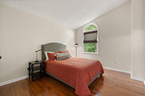 a bedroom with a bed with an orange bedspread and a window at 5 Minutes from Hospitals and UK! in Lexington