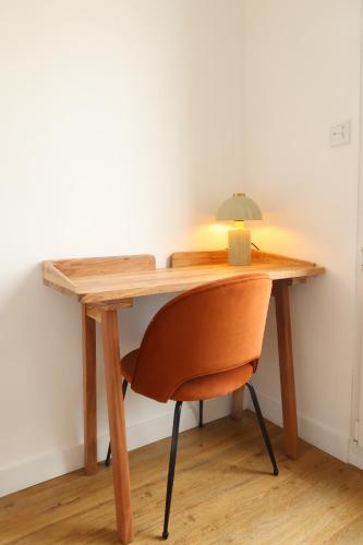 a wooden desk with a chair and a lamp at Le Clos Normand in Saint-Aubin-sur-Mer