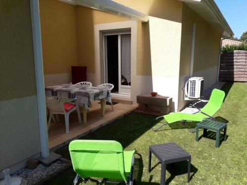 une terrasse avec des chaises vertes, une table et des chaises dans l'établissement Le coin paisible, à Gujan-Mestras