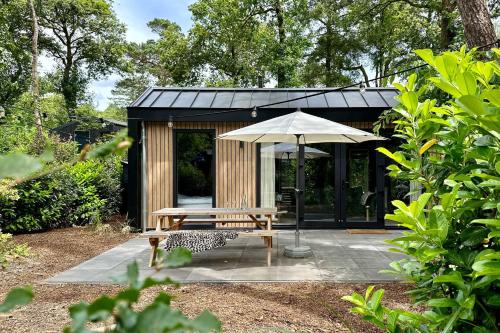 a wooden bench and an umbrella in a garden at Summ Lodge - luxe tiny boutique lodge Veluwe in Nunspeet