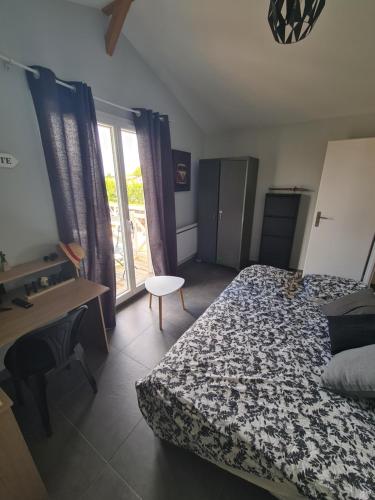 une chambre avec un lit, un bureau et une fenêtre dans l'établissement Chambre avec balcon sur La Teste de Buch, à La Teste-de-Buch