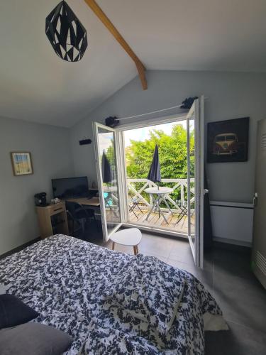 une chambre avec un lit et une porte ouverte sur un patio dans l'établissement Chambre avec balcon sur La Teste de Buch, à La Teste-de-Buch
