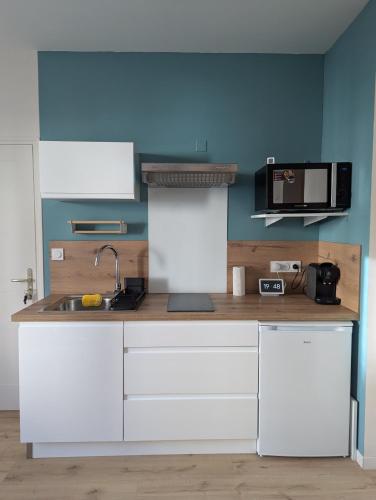 une cuisine avec des armoires blanches et un micro-ondes dans l'établissement Les Talards - 5 mn à pieds gare TGV, à Saint-Malo
