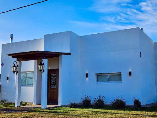 a white building with a brown door on the side at Puesta de Sol Casa Quinta in Azul