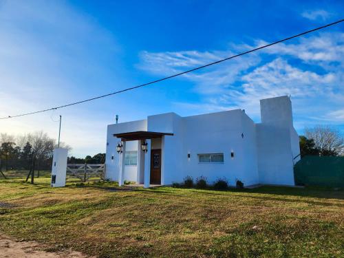a white building in a field with a blue sky at Puesta de Sol Casa Quinta in Azul