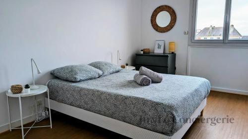 une chambre blanche avec un lit et un miroir dans l'établissement Elégant Appartement au Coeur de Redon, à Redon