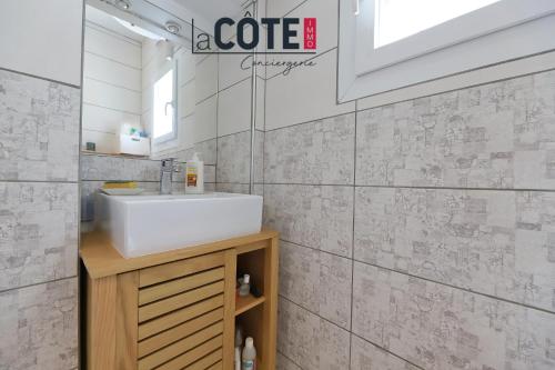 une salle de bain blanche avec un lavabo et un miroir dans l'établissement Les Pins, à Sausset-les-Pins