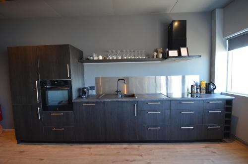 a kitchen with black cabinets and a microwave and a sink at LL Properties - TB24 Nest in the North in Akureyri