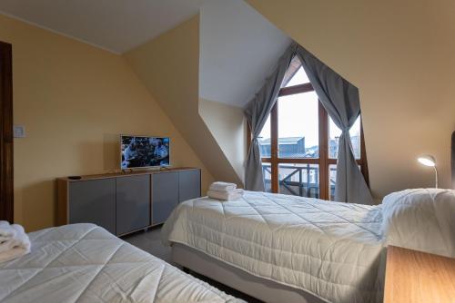 a bedroom with two beds and a tv and a balcony at Gente del Sur - Odino in Ushuaia