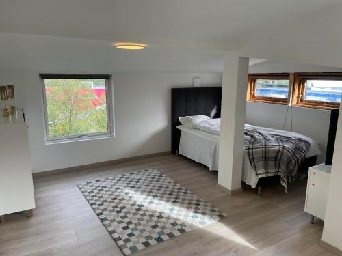 a bedroom with a bed and two windows and a rug at SelVik in Bergen