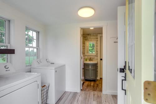 Un baño blanco con lavabo y espejo. en Ohio Farmhouse Retreat with Fire Pit and Patio, en Monroeville