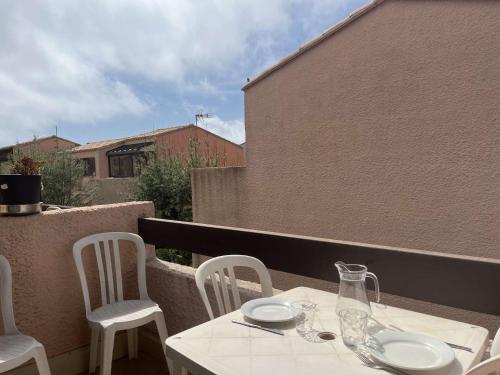 une table blanche et des chaises sur un balcon dans l'établissement Appart Studio mezz 3 couchages PORT LEUCATE NATURISME PL010-731, à Port-Leucate
