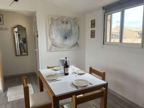 une salle à manger avec une table avec des chaises et une bouteille de vin dans l'établissement Appart 3 pièces 2 couchages PORT LEUCATE NATURISME PL010-071, à Leucate