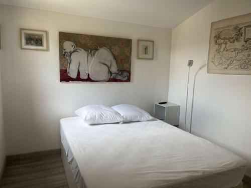 une chambre avec un lit blanc avec un tableau sur le mur dans l'établissement Appart 3 pièces 2 couchages PORT LEUCATE NATURISME PL010-071, à Leucate
