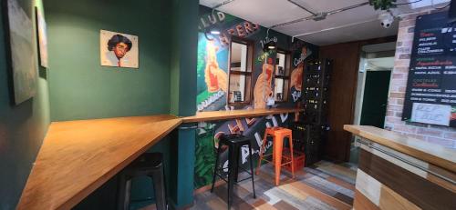 a bar with a green wall and some stools at The Wandering Paisa in Medellín