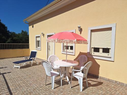 a table with chairs and an umbrella on a patio at Casa do Pastana in Ancião