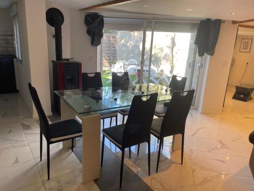 a dining room with a glass table and black chairs at Villa bord de mer deux ch sdb privative in Agde