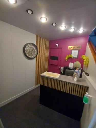 a reception desk in a room with a pink wall at Hotel Le Splendid in Troyes