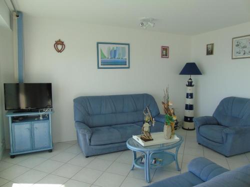 un salon avec deux canapés bleus et une table dans l'établissement L'Aloha, à Plage-des-Demoiselles