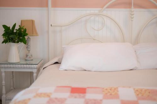 a white bed with a pillow and a table with a lamp at Terrace Inn and 1911 Restaurant in Petoskey