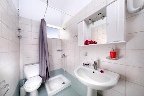 a white bathroom with a toilet and a sink at Vergonis Studios in Koropi