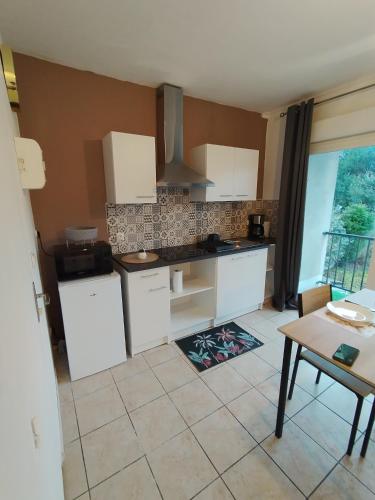 une cuisine avec des armoires blanches, une table et une fenêtre dans l'établissement grand studio, à Limoges